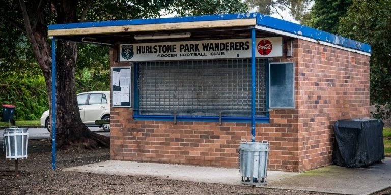Small brick canteen building with blue awning and Hurlstone Park Wanderers sign