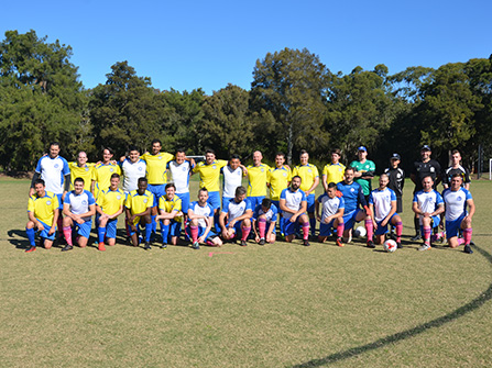 mens soccer teams in yellow and blue and white and blue on pitch lined up posing for photo